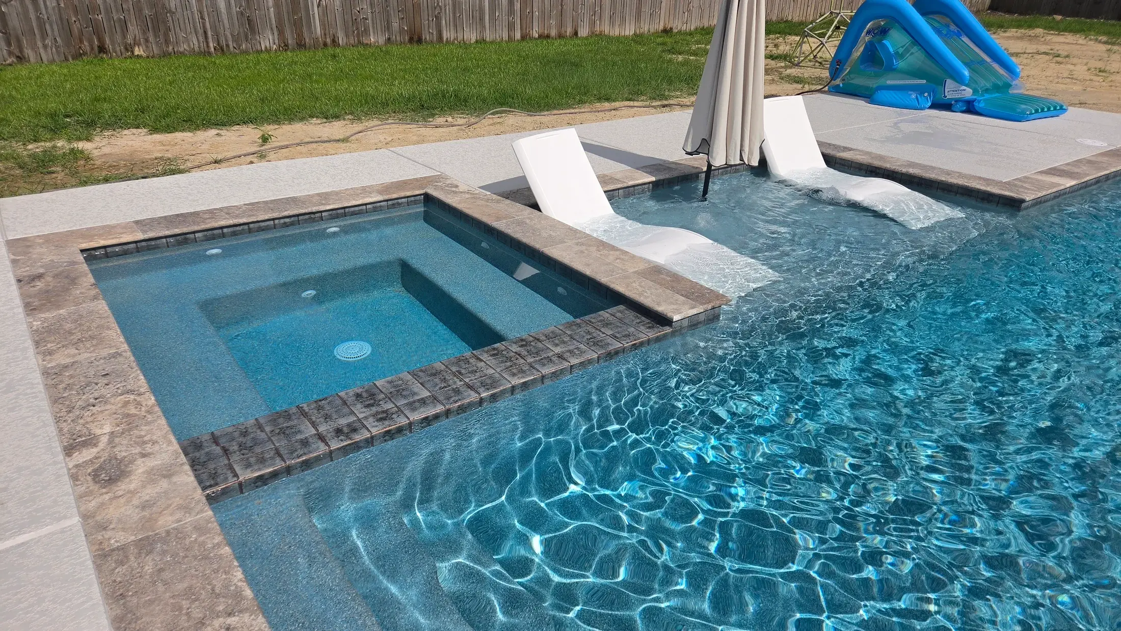 Clearwater tanning ledge with two in-water lounge chairs beside a recessed spa